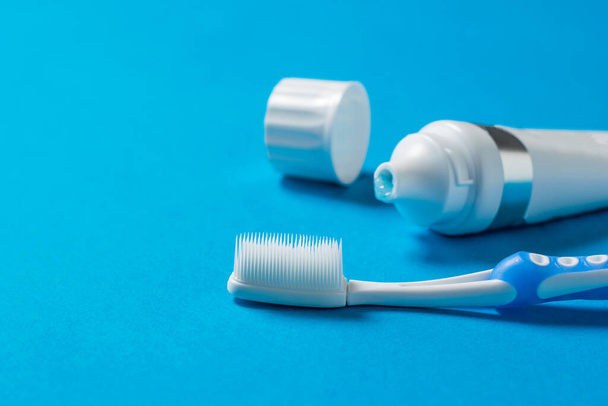 Un cepillo de dientes con cerdas de silicona y un tubo de pasta de dientes sobre un fondo azul
. - Foto, Imagen