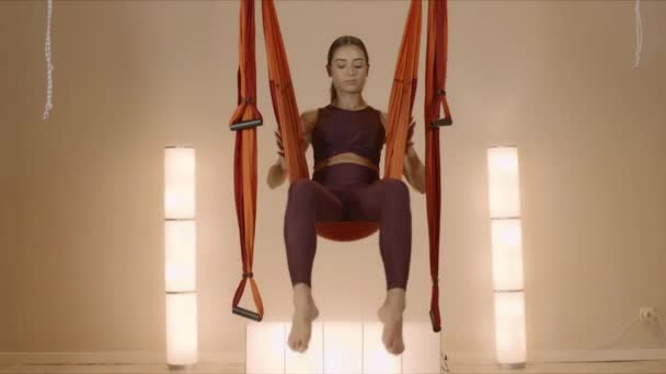 Meisje ondersteboven hangend in hangmat. Dame doet omgekeerde duif pose in hangmat - Video