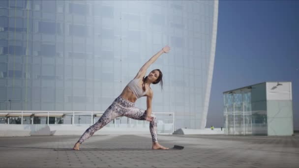 Chica realizando yoga en la calle. Mujer haciendo extendido lado ángulo pose en la calle
 - Metraje, vídeo