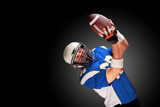 American Football-Spieler in Bewegung mit dem Ball auf schwarzem Hintergrund mit heller Linie, Kopierraum. Das Konzept des Spiels ist American Football, Bewegung. - Foto, Bild