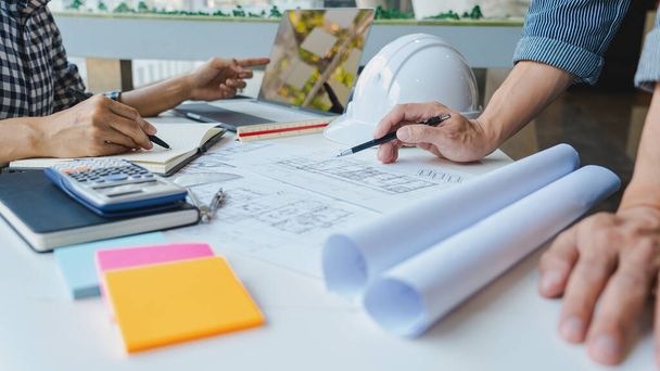 Ingenieur Hand Drawing Plan On Blue Print mit architektonischer Ausstattung diskutiert die Grundrisse über Baupläne am Tisch in einem modernen Büro - Foto, Bild