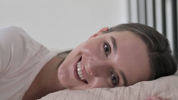 Веселая молодая женщина в постели улыбается перед камерой
 - Фото, изображение