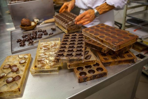 Pastelero de chocolate haciendo una presentación de chocolate con granos de cacao, vainas de cacao y moldes de chocolate en el museo de chocolate en Bruselas, Bélgica
 - Foto, Imagen