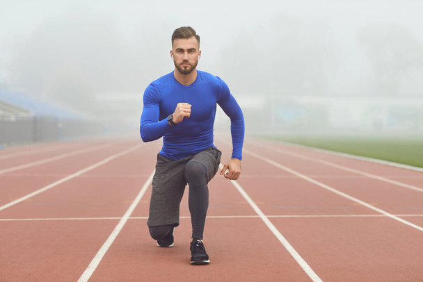 The guy the athlete does squats in the stadium in the fog - Foto, imagen
