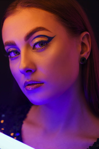 Toned portrait of beautiful woman with neon lamp on dark background - Valokuva, kuva