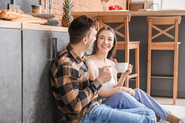若い夫婦は台所で一緒にお茶を飲む - 写真・画像