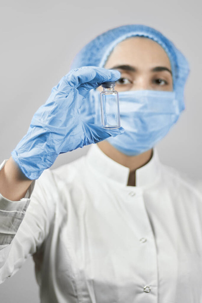 Ärztin, Wissenschaftlerin oder Virologin in medizinischer Schutzmaske und Handschuhen mit Coronavirus-Impfstoff nach langen Forschungen. Gesundheitshelfer hält Covid-19-Impfstoff hoch - Foto, Bild