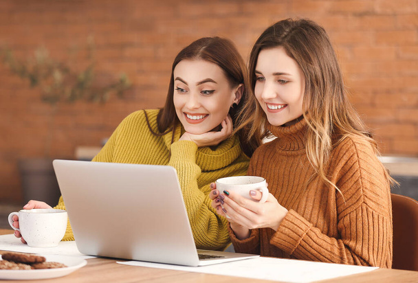 Giovani donne in maglioni caldi e con laptop a casa
 - Foto, immagini