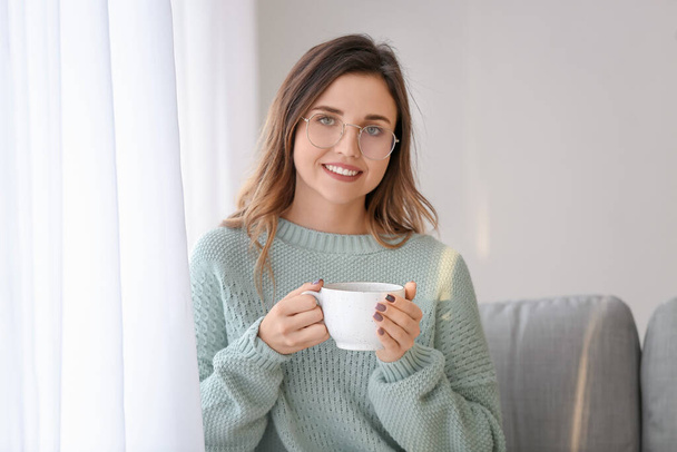 Nuori nainen lämpimässä villapaita juo teetä kotona
 - Valokuva, kuva