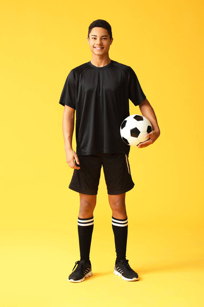 Mladý afroamerický fotbalista na barevném pozadí - Fotografie, Obrázek