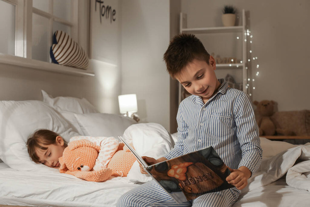 Kleines Mädchen schläft ein, während ihr Bruder zu Hause Gute-Nacht-Geschichte vorliest - Foto, Bild