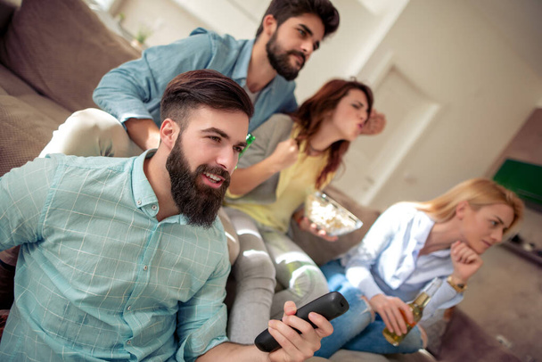 Concepto de amistad, ocio y gente - amigos felices con cervezas sentados en el sofá y viendo fútbol en la televisión en casa. - Foto, imagen