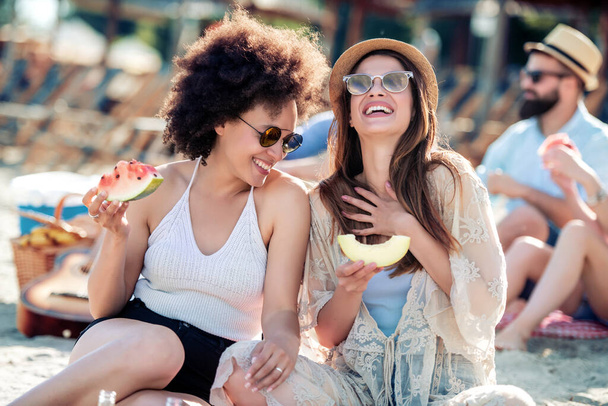 Dvě krásné dívky na pláži jíst melouny a meloun. - Fotografie, Obrázek