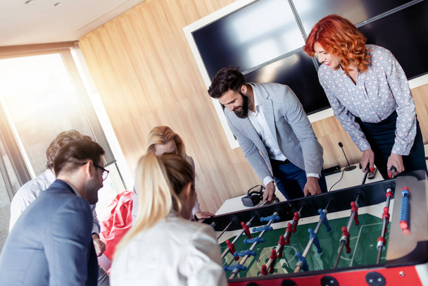 Οι επιχειρηματίες έχουν μεγάλη στιγμή μαζί.Συνάδελφοι παίζουν επιτραπέζιο ποδόσφαιρο στο σύγχρονο γραφείο. - Φωτογραφία, εικόνα