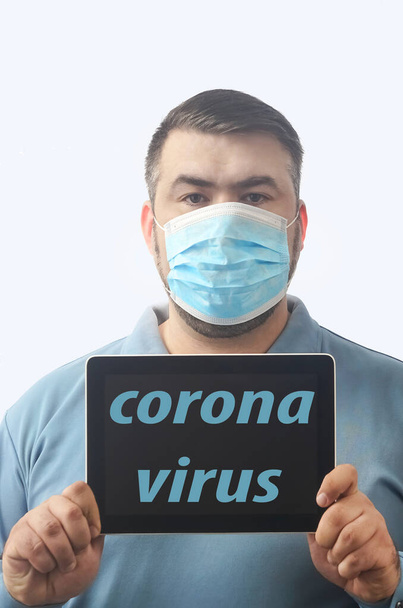 Man with mask to protect him from Coronavirus. Corona virus pandemic. Man hold  mask before face. Young man with mask standing. Person in hood with medical mask. isolated on white background. tablet computer in hands. inscription on screen. - Fotoğraf, Görsel