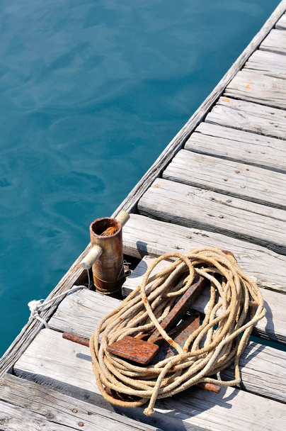Cuerda marina enrollada en muelle de madera
 - Foto, imagen