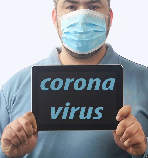 Man with mask to protect him from Coronavirus. Corona virus pandemic. Man hold  mask before face. Young man with mask standing. Person in hood with medical mask. isolated on white background. tablet computer in hands. inscription on screen. - Fotoğraf, Görsel