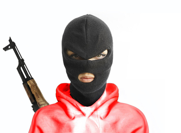 woman wearing red  hoodie, balaclava or black mask  isolated on white  background . machine gun hangs behind back.  - Photo, Image