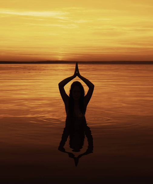 Mujer joven silueta practicando yoga en la playa. manos por encima de la cabeza
.  - Foto, imagen