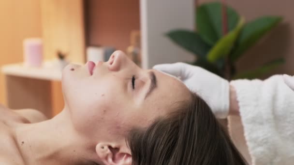 Hübsche Frau erhält Gesichtsmassage im Wellness-Salon - Filmmaterial, Video