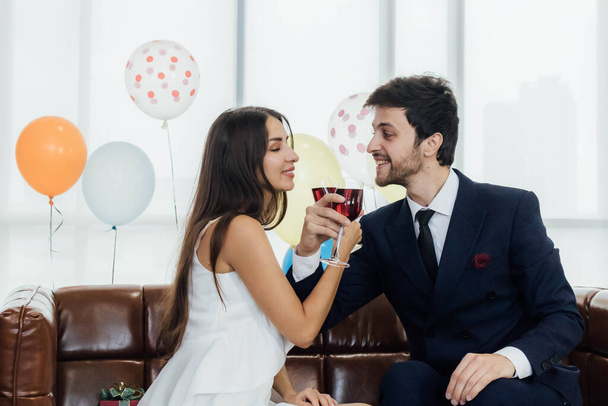 Νεαρό ζευγάρι γιορτάζει το νέο έτος μαζί, πίνοντας κρασί μαζί. - Φωτογραφία, εικόνα