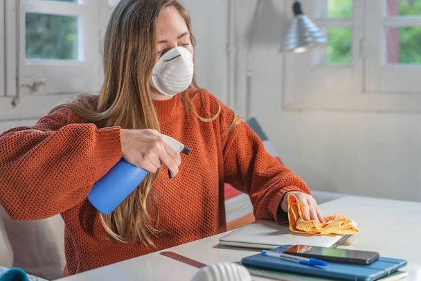 Coronavirus. Woman with face mask and rubber gloves cleaning stuff with a disinfectant at home during the coronavirus epidemic. Infection prevention and control of epidemic. Disinfect your house. - Foto, afbeelding