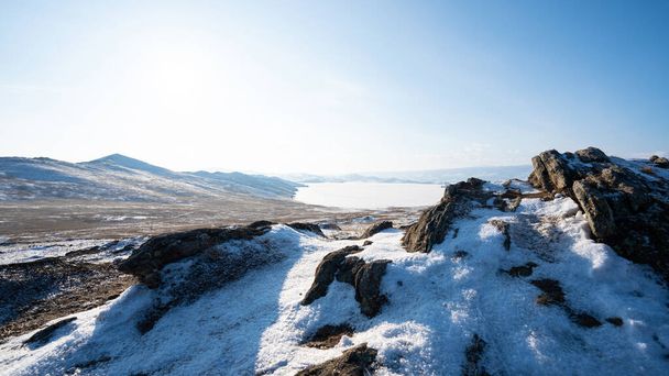 Lago visto das montanhas cobertas de gelo. As montanhas rochosas estão cobertas de neve. Bela paisagem de montanhas e céus. Lago Baikal, Rússia
.  - Foto, Imagem