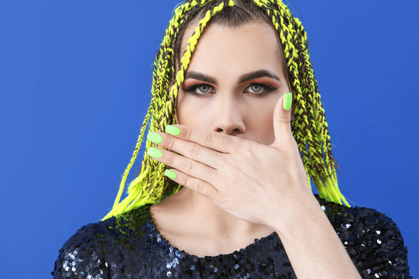 Retrato de mujer transgénero joven cubriendo la boca en el fondo de color
 - Foto, Imagen
