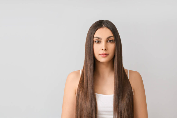 Nuori nainen, jolla on kauniit suorat hiukset harmaalla taustalla
 - Valokuva, kuva