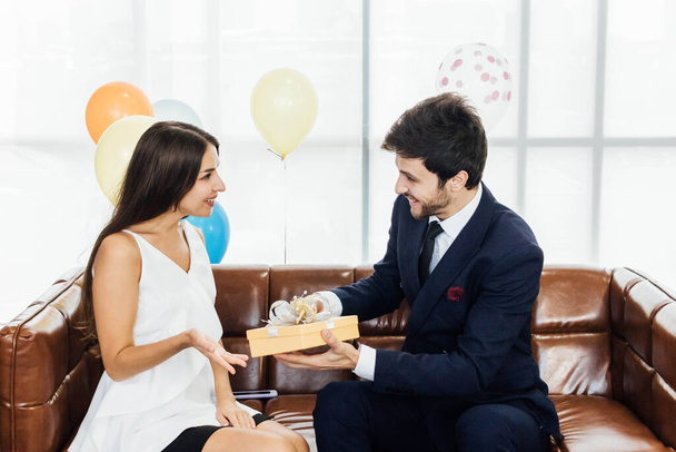 Young couple celebrating new year together, boyfriend gives a present to girlfriend. - Fotó, kép