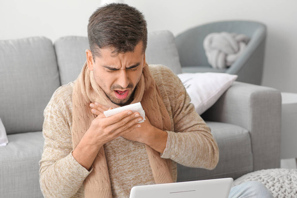 Coughing young man with laptop at home - Foto, imagen