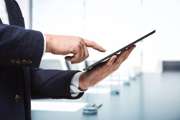 Man presses on the screen of a digital tablet in sunny boardroom, close up. Online technology concept - Φωτογραφία, εικόνα