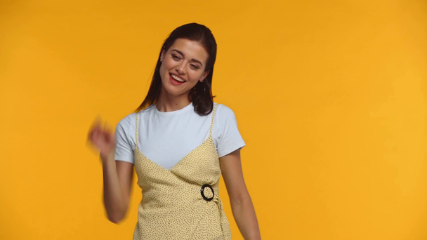 Веселая девушка машет руками и смотрит на камеру, изолированную на желтый
 - Кадры, видео