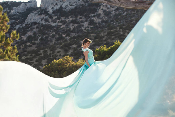 Bride in nature in the mountains near the water. Dress color Tiffany. The bride is playing with his dress. - Фото, зображення