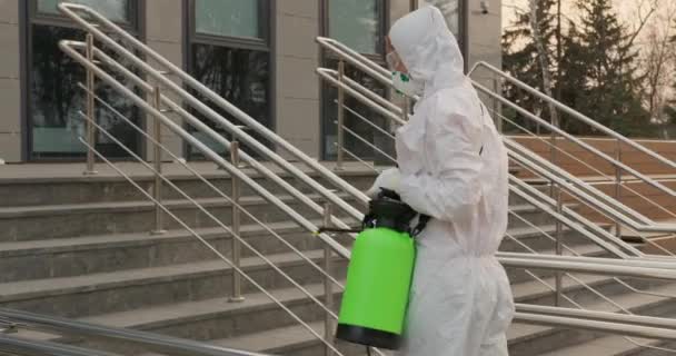 Worker in a protective suit disinfects surfaces from coronavirus. Antibacterial sanitary measures on quarantine. - Footage, Video