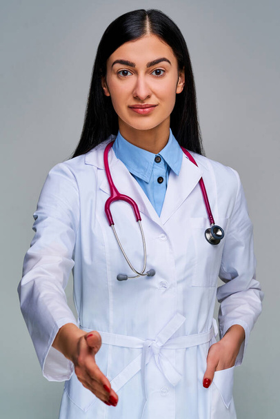 Woman with black long hair in a medical coat with red nails looking at the camera - Фото, зображення