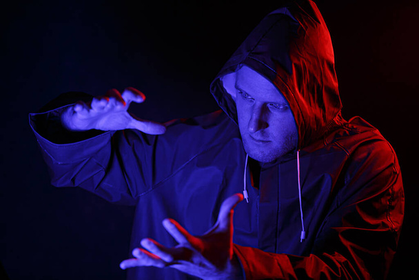 Karanlık bir odada koruyucu takım elbiseli bir adam. Cadılar Bayramı imajı. Virüs koruması. Renkli ışıklarla aydınlatılmış - Fotoğraf, Görsel