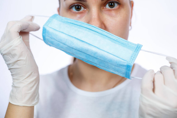 woman health worker demonstrates how to wear a protective medical surgical mask against the virus. Isolated on white background - Фото, зображення