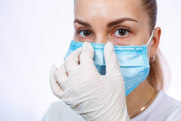 女性の健康労働者はウイルスに対して保護医療外科用マスクを着用する方法を示しています。白地に隔離された - 写真・画像