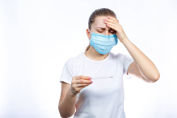 beteg nő orvosi maszkban, lázmérővel a kezében, amit a vírus ellen kezeltek. Fehér alapon elszigetelve - Fotó, kép