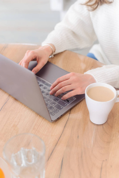 Woman is typing on keyboard of laptop or notebook at home freelance, check electronic mail, get some information for shopping online or operate of banking on web. Cup of coffee. - Fotó, kép