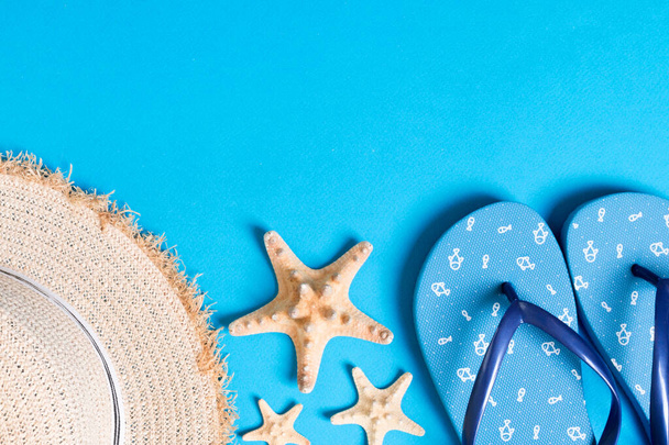 Summer beach flat lay accessories. Sunscreen straw hat, flip flops and seashells on colored Background. Travel holiday concept with copy space. - Photo, Image