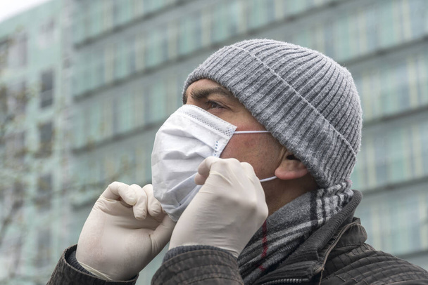 έξαρση ασθένειας, κοβίδιο του ιού της στέψης-19 πανδημία. Κοντινό πορτραίτο ενός ενήλικου άνδρα με χειρουργική προστατευτική μάσκα στο πρόσωπό του - Φωτογραφία, εικόνα