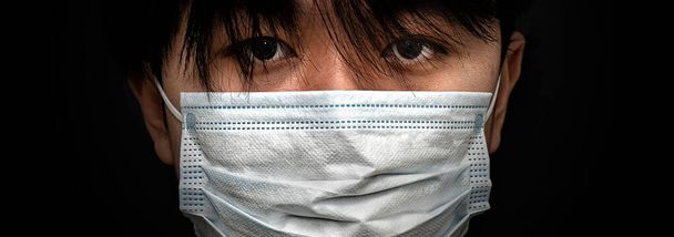 Closeup of serious looking Asian child wearing a face mask - Foto, imagen