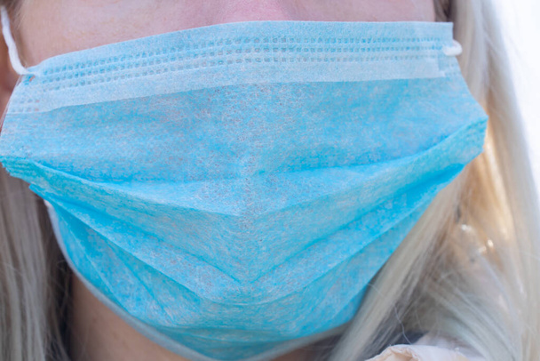 closeup of a young Ukrainian woman in a medical mask on her face during the pandemic outdoors - Photo, Image