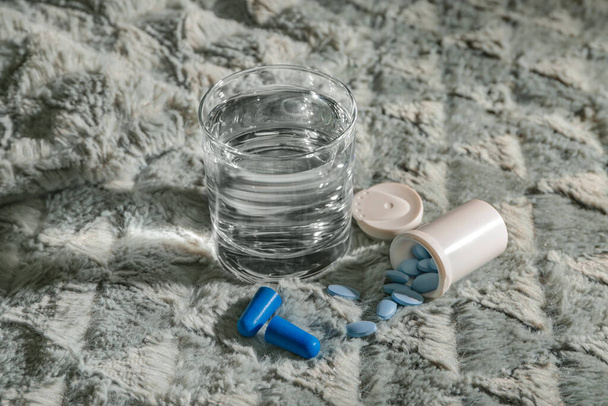 Glass of water and sleeping pills on bed - Foto, afbeelding