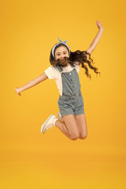 Spirit of freedom. Active girl feel freedom. Fun and relax. Feeling free. Carefree kid. Summer holidays. Jump of happiness. Small girl jump yellow background. Enjoy freedom. Childrens day concept - Foto, imagen