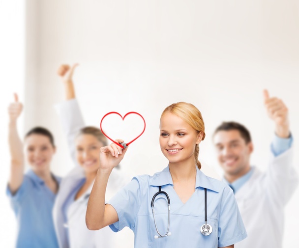 Smiling doctor or nurse drawing red heart - Photo, image