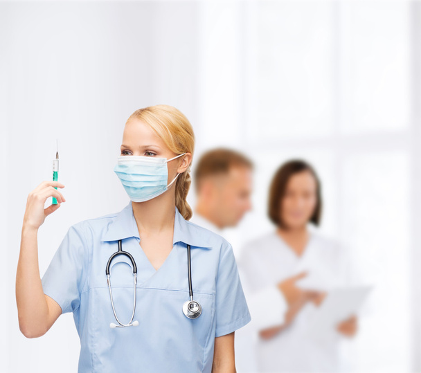 Female doctor or nurse in mask holding syringe - Foto, Imagen