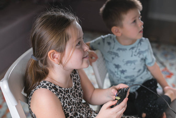 かわいい女の子と男の子が家でビデオゲームをしています。家族は家にいる。自己分離だ。コロナウイルスの流行隔離 - 写真・画像